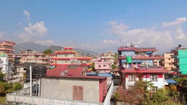 Nepal 'in Pokhara şehrinde geleneksel Nepal yerleşim birimlerinin çoklu katlı evlerini gösteren hava zoom. Nepal 'de konaklama ve mülk. Binaların üzerinden Annapurna dağ sıraları manzarası