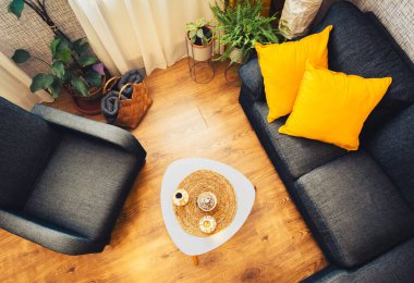 Üst kattaki, sıcak, gri kanepeli, sarı yastıklı, İslami espresso bardaklı şık kahve masalı, iki kişilik hazır kahve fincanı olan bir ev oturma odası..