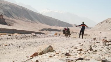 Arkadan bakıldığında maceracı beyaz erkek bisiklet tek başına Pamir 'in ücra Pamir Dağları' ndaki Bartang Vadisi 'nde turluyor. Pamir otoyolu macera rotası