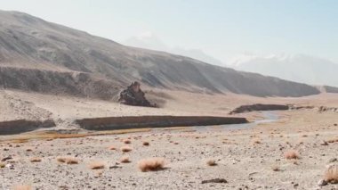 Dört pannier çantasına yüklenmiş kırmızı bisiklet. Çakıl yolunun kenarında duruyor. Etrafı vahşi Pamir dağlarıyla çevrili. Yalnız macera seyahati