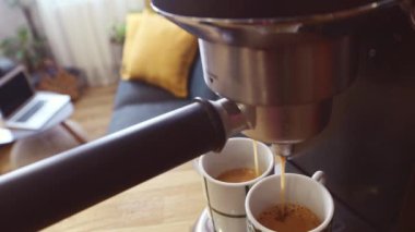 Hızlı hareket eden kahve makinesi sabah kahvesini iki güzel dekore edilmiş espresso bardağına doldurur.