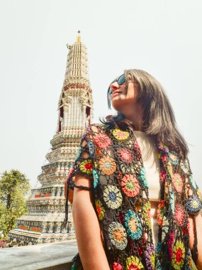 Young woman traveler blogger pose by beautiful buddhist temple Wat Arun - famous travel destination in Bangkok, Thailand. Tourist sightseeing south-east asia historical landmarks clipart