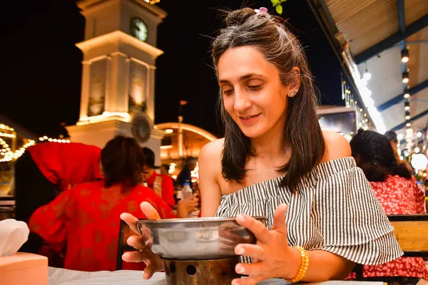 stock image Close up excited caucasian woman tourist sit in asian restaurant try favorite Thai dish Tom Yum hot soup with shrimps in local food restaurant. Thailand vacation food tour concept