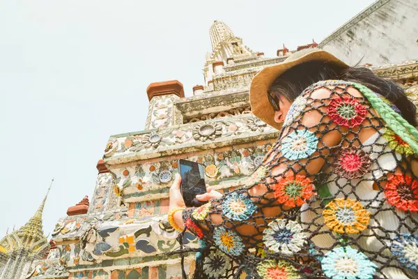 Genç kadın gezgin blogcu güzel Budist tapınağı Wat Arun 'un videolarını çekiyor. Tayland, Bangkok' taki ünlü seyahat merkezi. Güneydoğu Asya 'da tarihi yerleri gezen turistler