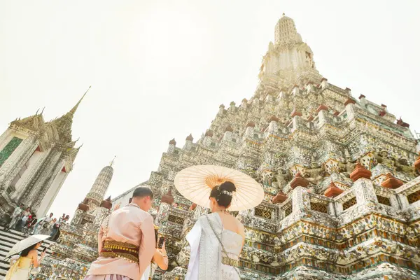 Bangkok, Tayland - 11 Şubat 2024: Genç Taylandlı çift Wat Arun 'un güneşli bir günde yaptığı fotoğraf çekimi için geleneksel kıyafetler giyerler.