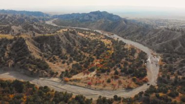 Hava kuşları, nehir vadisinde, manzaralı sonbahar manzaralı, S şeklindeki yolda giden 4x4 aracı görüyor. Aşırı off-road macera yolculuğu