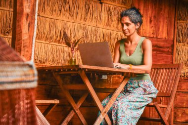 Kafkasyalı genç hippi kadın oturur bilgisayar serbest çalışır, seyahat blogu yazar ya da internet araştırması yapar, güneydoğu Asya tropikal adalarında seyahat ederken internetten çalışır.