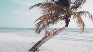 Kapalı kapılar ardında genç bir kadın güneşli bir günde kumsaldaki palmiye ağacının altında tatil için okyanus manzaralı bir yerde dinleniyor. Kamboçya 'daki ünlü Koh Rong adası.