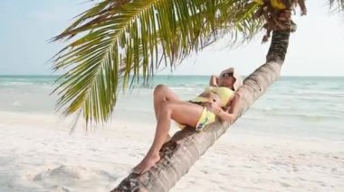Kapalı kapılar ardında genç bir kadın güneşli bir günde kumsaldaki palmiye ağacının altında tatil için okyanus manzaralı bir yerde dinleniyor. Kamboçya 'daki ünlü Koh Rong adası.