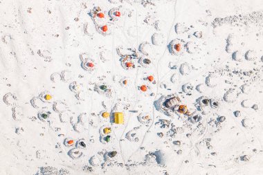 Aerial top down view Bethlemi Hut or meteo station base camp with colorful yellow orange tents in snow. Climbing Mount Kazbek in Kazbegi national park concept clipart