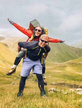 Beyaz erkek ve kadın yürüyüşçüler dağ manzarası afişinde mutlu yürüyüşler. Yazın açık havada gezen çiftlerin panoramik portresi. Sonbaharda birlikte dağlara seyahat eden çift.