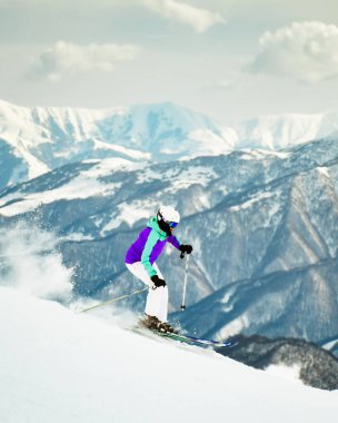 Alpler 'de yokuş aşağı kayak yapan kadın kayakçının dinamik bir resmi. Aktif kış tatili, bulutlu bir günde yokuş aşağı kaymak. Pistte kayak sürüşleri Taze kar girdaplarıyla