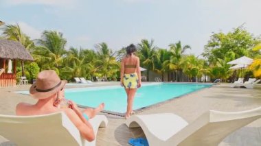 Uzaklaşan Avrupalı genç çift havuz kenarında dinleniyor birlikte tropik ada lüks tatil beldesinde