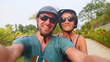 Kamboçya - 15 Mart 2024: Güneydoğu Asya 'da tropikal bir yolculukta scooter sürerken akıllı telefon selfie' si çeken mutlu beyaz çifti kapatın.