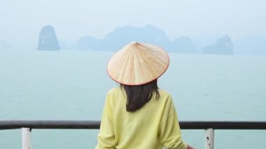 Vietnam 'daki Halong Körfezi Milli Parkı' nda, binlerce küçük ve büyük kireçtaşı adasından oluşan bir yolcu gemisinde duran kadın turist. Vietnam 'a seyahat. Heyecanlı eller havaya.