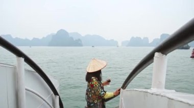 Vietnam 'daki Halong Körfezi Milli Parkı' nda, binlerce küçük ve büyük kireçtaşı adasından oluşan bir yolcu gemisinde duran kadın turist. Vietnam 'a seyahat. Heyecanlı eller havaya.