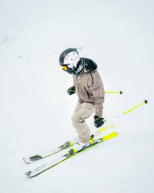 Piste kayak yapan yan manzara kayakçısı. Kar yağışlı koşullarda izole edilmiş ve görüş mesafesi düşük beyaz kar.