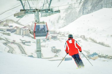 Yokuş aşağı kayan erkek kayakçı, karlı koşullarda hızla kabin kaldırarak dağ arkası gondola gidiyor. Gudauri kış tatili tatil köyü. Georgia 'ya seyahat. Kafkaslar