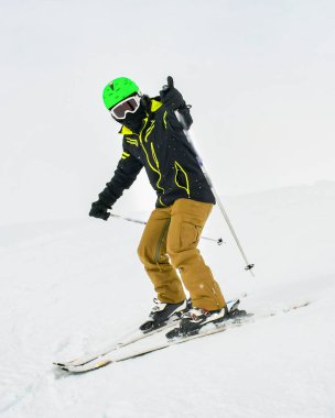 Alp kayağı. Yokuş aşağı giden kayakçı erkek kayakçı kışın izole edilmiş beyaz kayak pistinde baş parmağını kaldırdı. İyi bir erkek kayakçı.