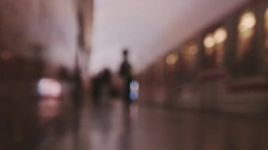 Mavi bir metro vagonu durağa yaklaşıyor, yolcular biniyor, arka plan bulanık. Seçici odak