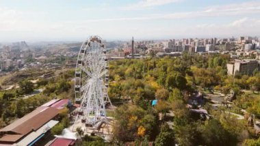 Erivan, Ermenistan - 19 Ekim 2024: Gökyüzü manzaralı ziyaretçiler, güneşli sonbahar gününde eğlence parkında atlıkarıncalara biniyorlar. Seyahat ve yapılacak işler Erivan konseptini ziyaret ediyor