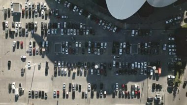 Sabah, ofis binası ve arabalarla dolu büyük bir otoparkta, hızlandırılmış hava statik görüntüsü. Araçlar park edilmiş. Güneşli bir sabahta kalabalık otoparkta arabalar hareket ediyor. Yüksek kalite 4k