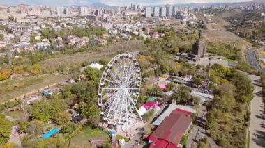 Erivan, Ermenistan - 19 Ekim 2024: Gökyüzü panoramik manzaralı dönme dolap Victory Park 'ta şehir manzaralı ve Erivan binalı. Güneşli bir sonbahar günü atlıkarıncalar her gün konsept yapacak şeyler yaparlar.