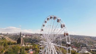 Erivan, Ermenistan - 19 Ekim 2024: Gökyüzü manzaralı dönme dolap Victory Park 'ta Erivan' ın manzaralı ve binalı. Güneşli bir sonbahar günü atlıkarıncalar her gün konsept yapacak şeyler yaparlar.
