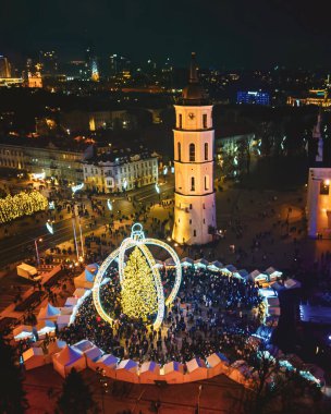 Vilnius, Litvanya - 30 Kasım 2024: Gökyüzü manzaralı katedral meydanı ve Xmas pazar ziyaretçileri Vilnius şehrinde güzel Xmas ağacı görüyorlar - 2025 Noel 'inin Avrupa başkenti.