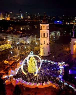 Vilnius, Litvanya - 30 Kasım 2024: Gökyüzü manzaralı katedral meydanı ve Xmas pazar ziyaretçileri Vilnius şehrinde güzel Xmas ağacı görüyorlar - 2025 Noel 'inin Avrupa başkenti.