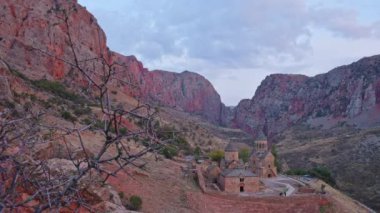 Zaman atlamalı panoramik manzara Noravank manastır kompleksi, 13. yüzyıl Ermeni manastırı. Kutsal Meryem Ana Kilisesi. Amaghu 'daki Noravank. Kızıl kayalıklar Arani köyünü dolduruyor. Ermenistan 'da turizm beldesi