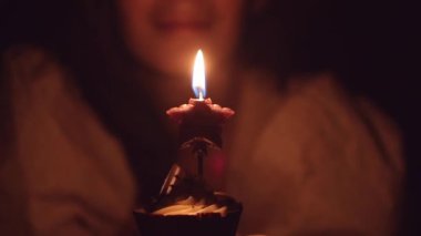 Kapalı bir yerde doğum günü pastasına mum üfleyen bir kadın. Kapalı bir odada izole edilmiş. Evde elinde mumlarla kek tutan gülümseyen bir kadın.