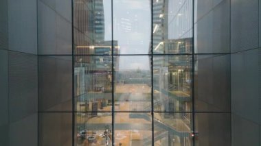 Vilnius, Litvanya - 28 Kasım 2024: hava manzaralı ofis çalışanı modern ofis içi yansımalarıyla cam iş binasında yürüyor. Anteja Tıp Kliniği. Telia telekomünikasyon şirketi