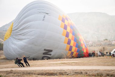 Goreme, Türkiye - 27 Aralık 2024: Balon şirketi çalışanı Kapadokya 'ya uçmadan önce sıcak hava balonunu çekmek için çok çalışıyor. Kapadokya balonları uçuş etkinliği iptali ve güvenlik hazırlıkları
