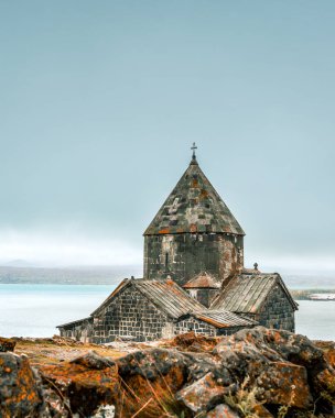Ermenistan, Sevan 'da eski bir Sevanavank kilisesinin manzarası. Sevan Gölü kıyısında dikey Ermeni Ortodoks simgesi