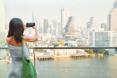Bangkok, Tayland - 11 Şubat 2024: Güneydoğu Asya 'nın popüler tatil beldesi Bangkok, Tayland' da güneşli bir günde nehrin üzerinde ünlü bir alışveriş merkezi manzaralı kadın turist standı fotoğrafı