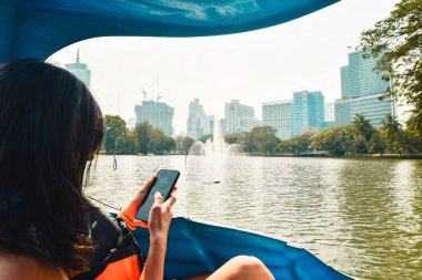 Dev monitör kertenkele sudayken, beyaz kadın dinlenme aktivitesinin tadını çıkarıyor. Bangkok 'taki en popüler park olan Lumpini Parkı' nı ziyaret edin. Silom 'un Merkezi İş Bölgesi