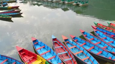 Pokhara 'da gündoğumunda sallanan geleneksel renkli Phewa Gölleri ahşap teknelerinin statik 4k zaman döngüsü. Phewa gölü tekne gezisi konsepti. Phewa rıhtımında çok renkli ahşap kayıklar ve katamaranlar.