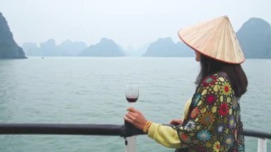 Kadın turist, Vietnam 'daki Halong Körfezi milli parkında binlerce küçük ve büyük kireçtaşı adasından oluşan tekne turunun keyfini çıkarıyor. Vietnam 'a seyahat. Heyecanlı eller havaya.