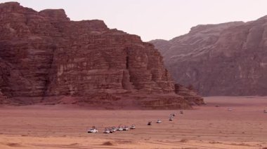 Ürdün - 15 Ekim 2022: Ürdün 'deki organize günbatımı turunda gün batımı perspektifinden 4wd araçlı Wadi romu çöl manzarası