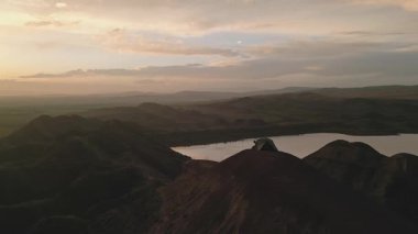 Sinematik hava manzaralı romantik çift birlikte oturur ve dışarıda çadırdan gün batımını izlerler. Romantik atmosfer bağlayıcı ilişkiler. Doğanın dinginliği, düzlükler