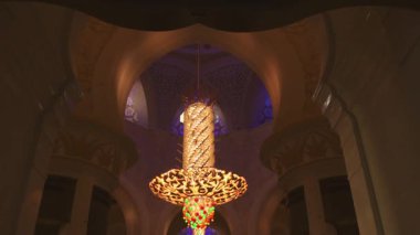Turistler ve ibadet edenler, Şeyh Zayed Büyük Camii 'nin içinde Swarovski kristal avizelerini yakalıyorlar. İslam mimarisinin ihtişamı ve modern lüks ışıklandırmanın birleşimi.