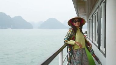 Vietnam 'daki Halong Körfezi Milli Parkı' nda, binlerce küçük ve büyük kireçtaşı adasından oluşan bir yolcu gemisinde duran kadın turist. Vietnam 'a seyahat. Heyecanlı eller havaya.