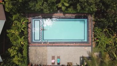 Sri Lanka 'nın derinliklerinde özel havuzda yüzen sakin manzaralı bir kadın. Ormandaki ıssız ve yemyeşil bir yer. Huzur içinde inzivaya çekilmek barış ve doğal güzellik sunar. Mükemmel kaçış.