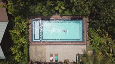 Sri Lanka 'nın derinliklerinde özel havuzda yüzen sakin manzaralı bir kadın. Ormandaki ıssız ve yemyeşil bir yer. Huzur içinde inzivaya çekilmek barış ve doğal güzellik sunar. Mükemmel kaçış.