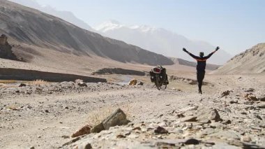 Arkadan bakıldığında maceracı beyaz erkek bisiklet tek başına Pamir 'in ücra Pamir Dağları' ndaki Bartang Vadisi 'nde turluyor. Pamir otoyolu macera rotası