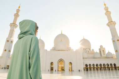 Abaya, Abu Dabi 'deki Şeyh Zayed' in Büyük Camii 'nde seyahat ederken, Müslüman elbisesi giymiş bir turist kız fotoğraf çekiyor.