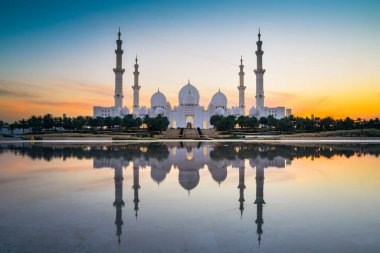 Şeyh Zayed Camii Abu Dabi, BAE 'de, alacakaranlıkta suda yansımasıyla. Gece mimarisinde mor mavi renkler.