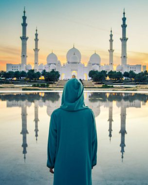 Abaya, Abu Dabi 'deki Şeyh Zayed' in Büyük Camii 'nde seyahat ederken, Müslüman elbisesi giymiş bir turist kız fotoğraf çekiyor.