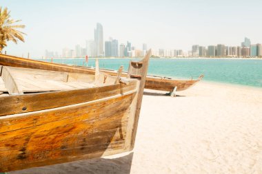 Abu Dabi silueti, Birleşik Arap Emirlikleri 'nin Abu Dabi kentindeki Heritage Village' da geleneksel balıkçı tekneleriyle birlikte. Çift plajın keyfini çıkarıyor ve BAE 'deki turistik yerleri ziyaret ediyor.